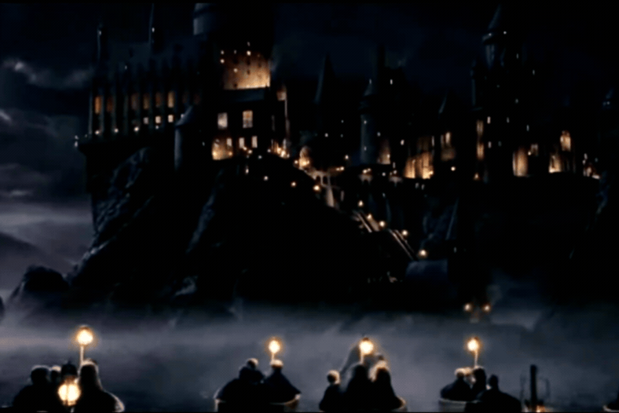 Castelo de Hogwarts iluminado à noite envolto por névoa, lembrando o universo mágico de Harry Potter com estudantes atravessando um lago em pequenos barcos em direção ao grande castelo medieval